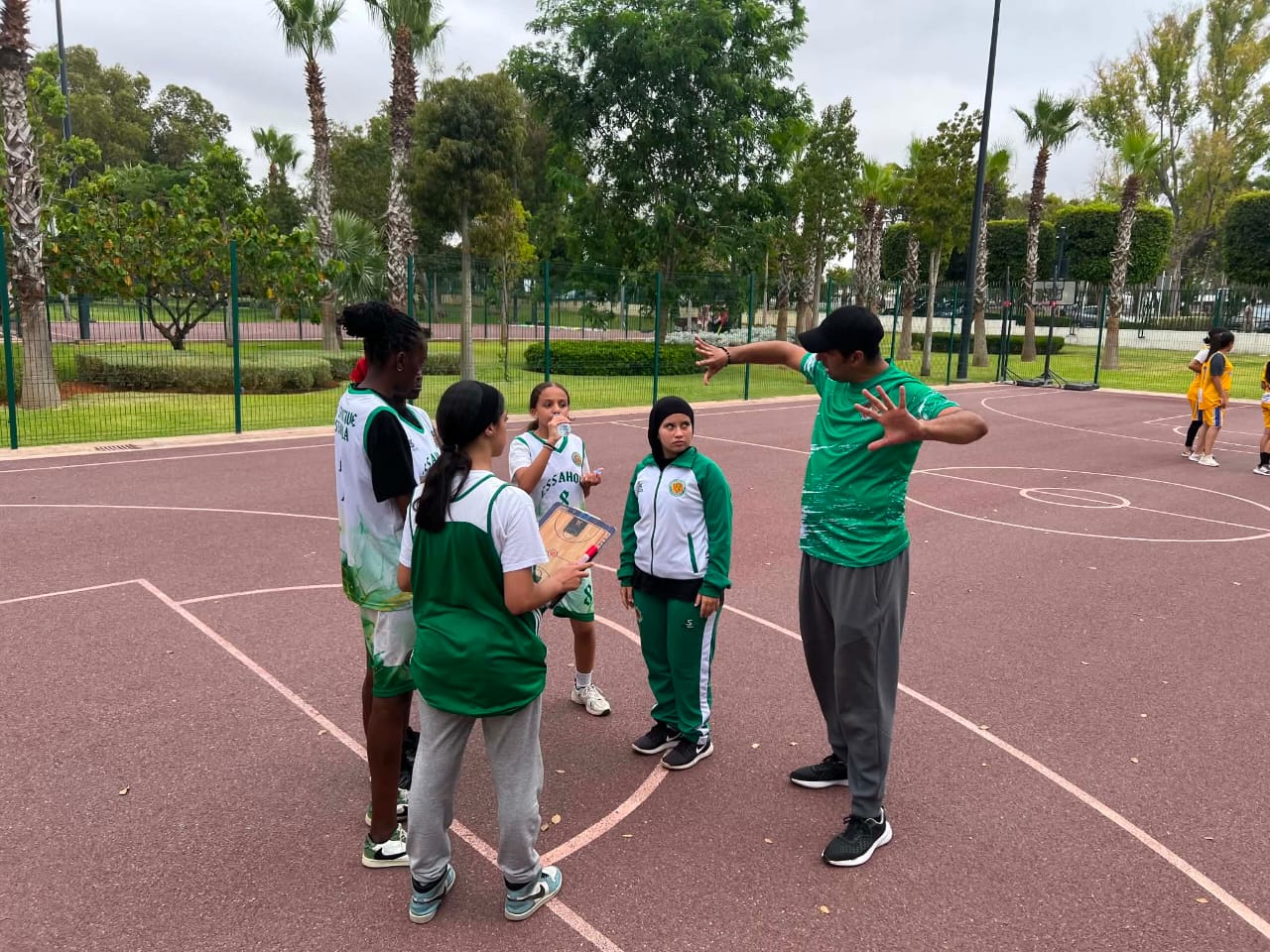 Explication des consignes tactiques sur plaquette par le coach aux jeunes basketteuses