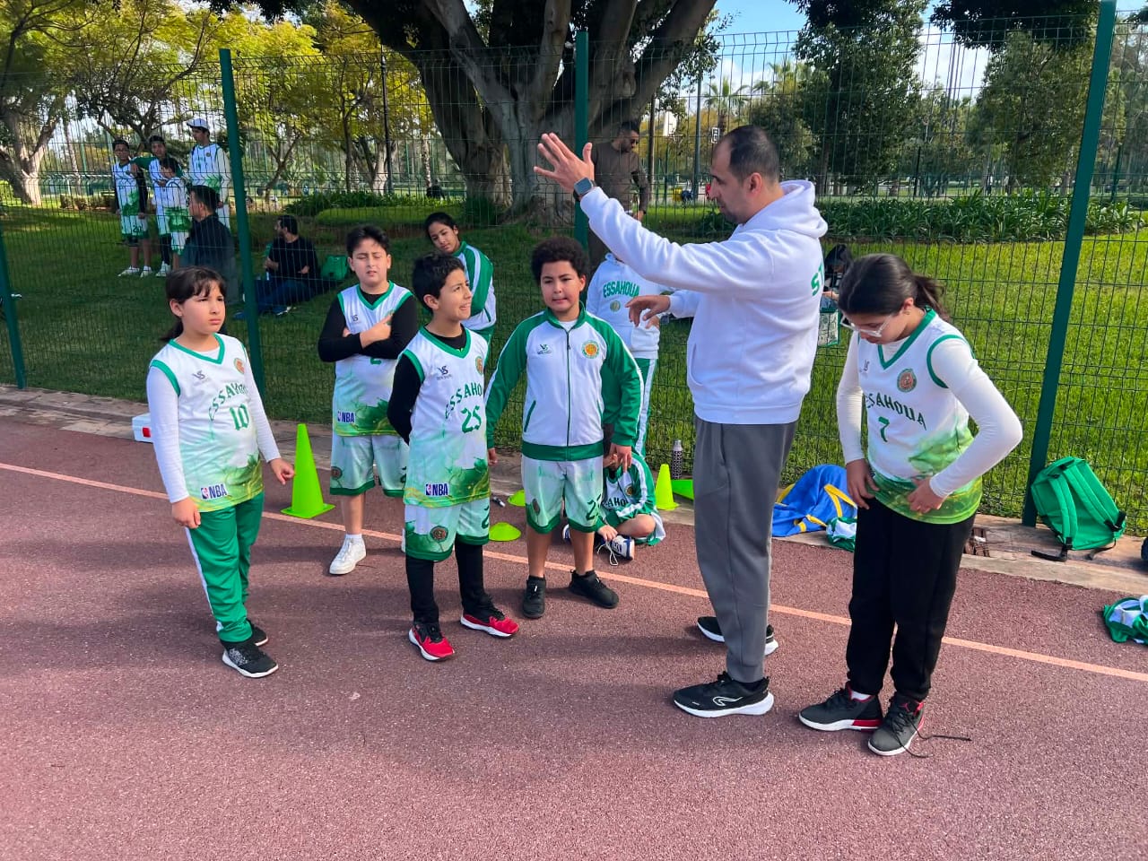 Entraîneur en plein briefing technique avec de jeunes basketteurs du club