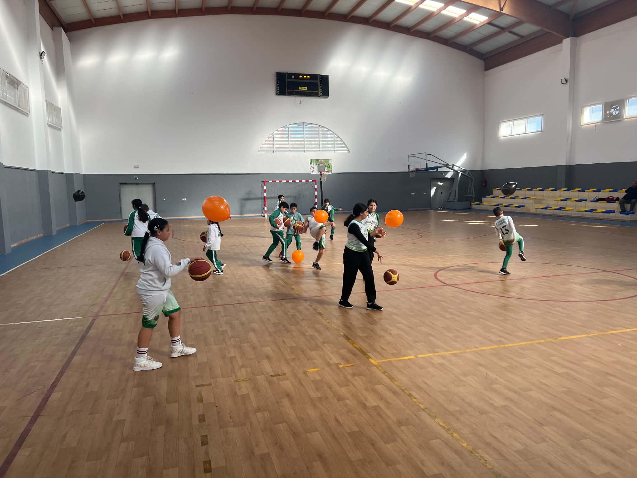 Échauffement ludique avec ballons de basket et baudruches dans la salle couverte
