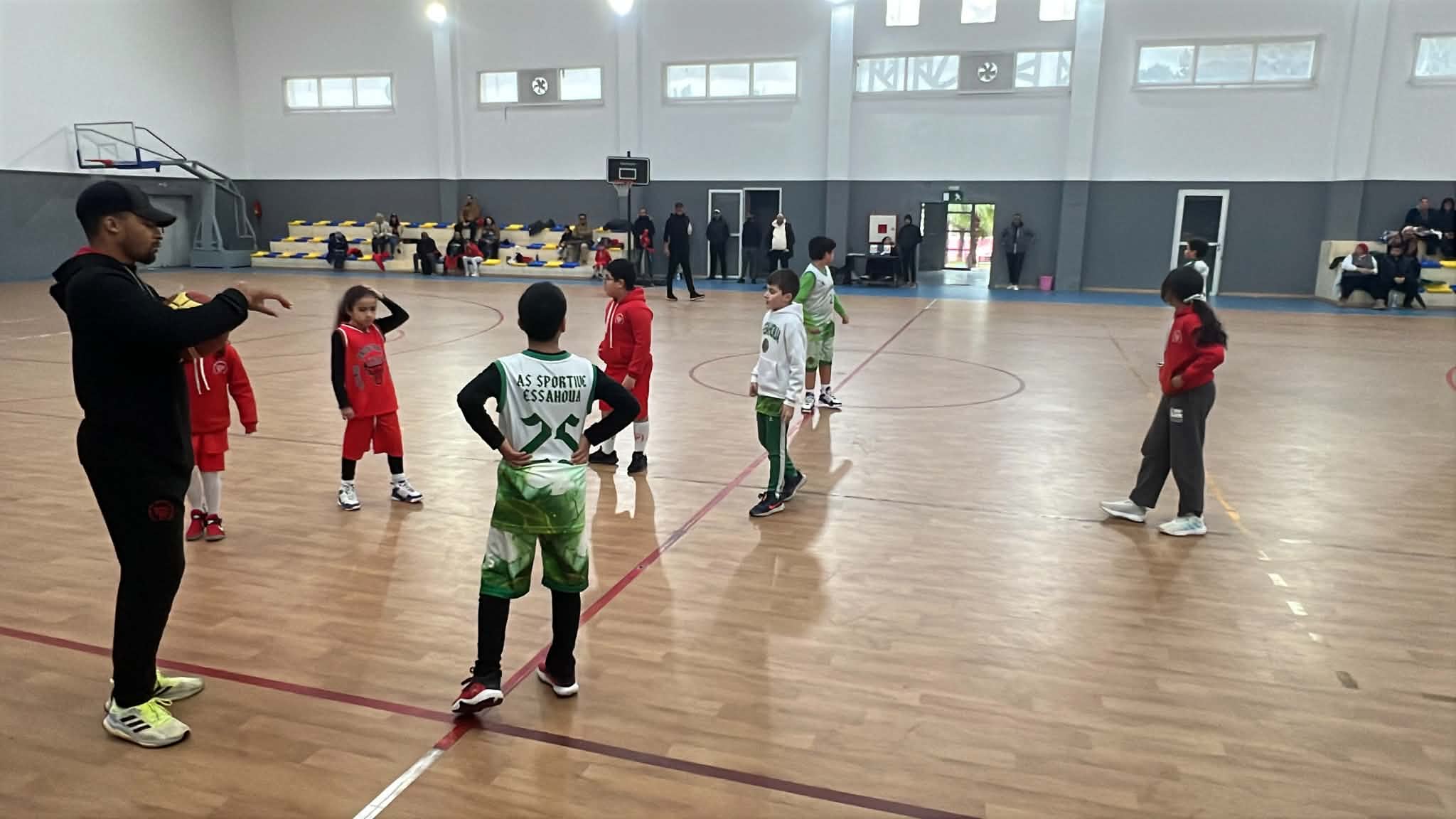 Entraîneur donnant des consignes tactiques aux enfants sur le terrain de basketball couvert