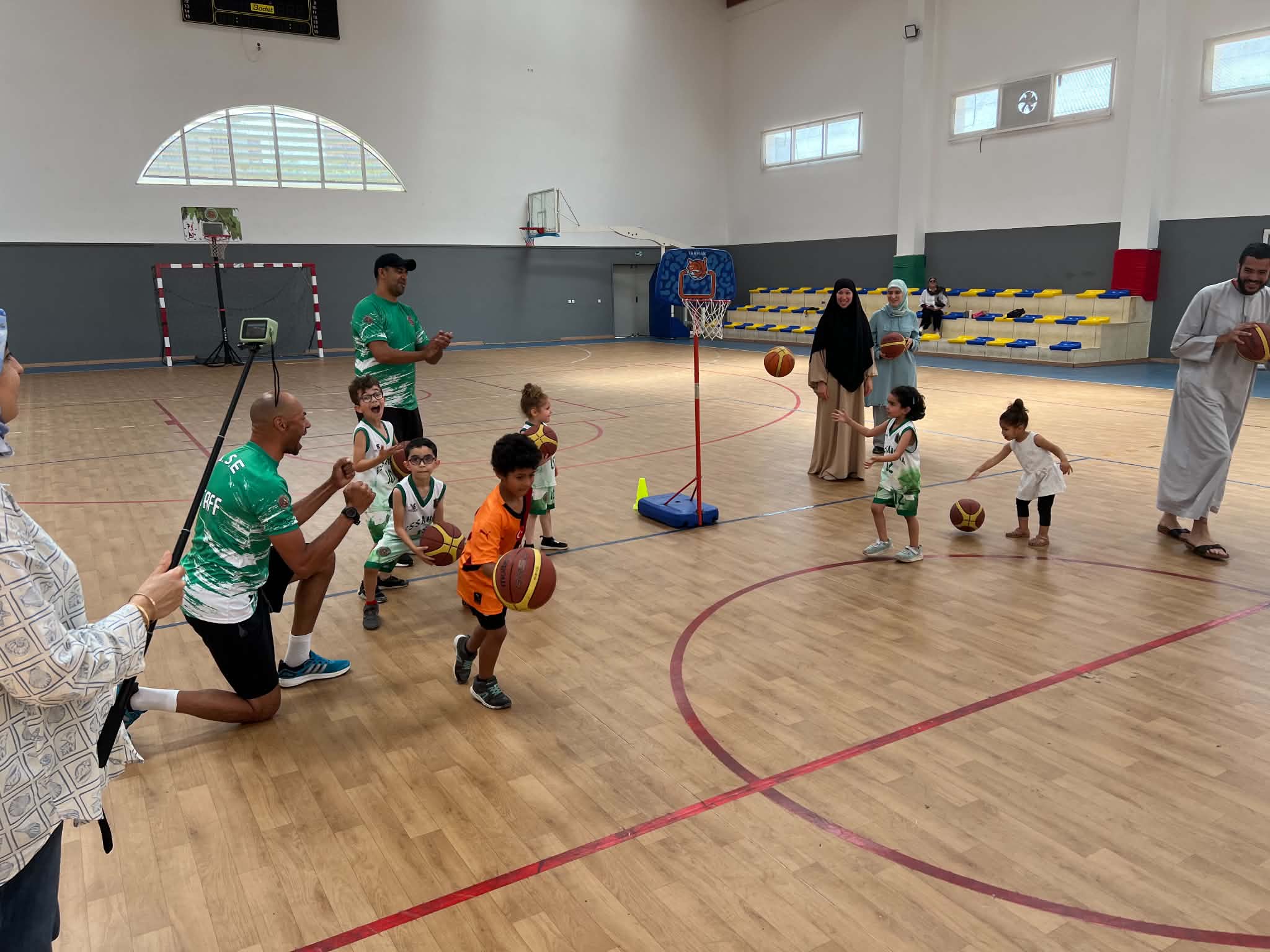 Initiation au basketball pour les tout-petits avec les entraîneurs autour d'un mini-panier