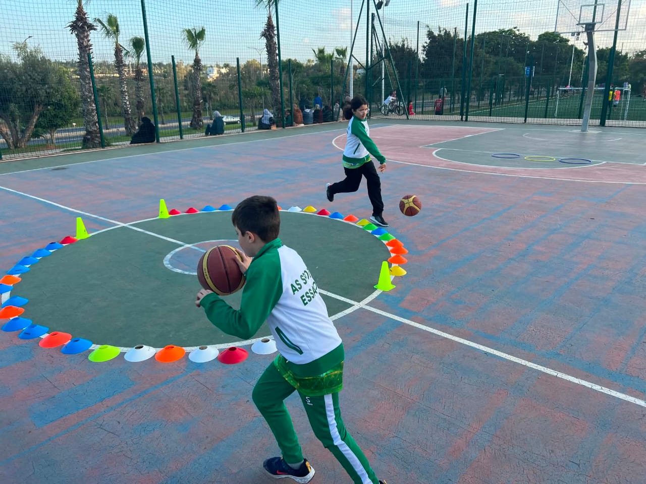Jeune basketteur en exercice de dribble entre les plots sur le terrain extérieur à Rabat