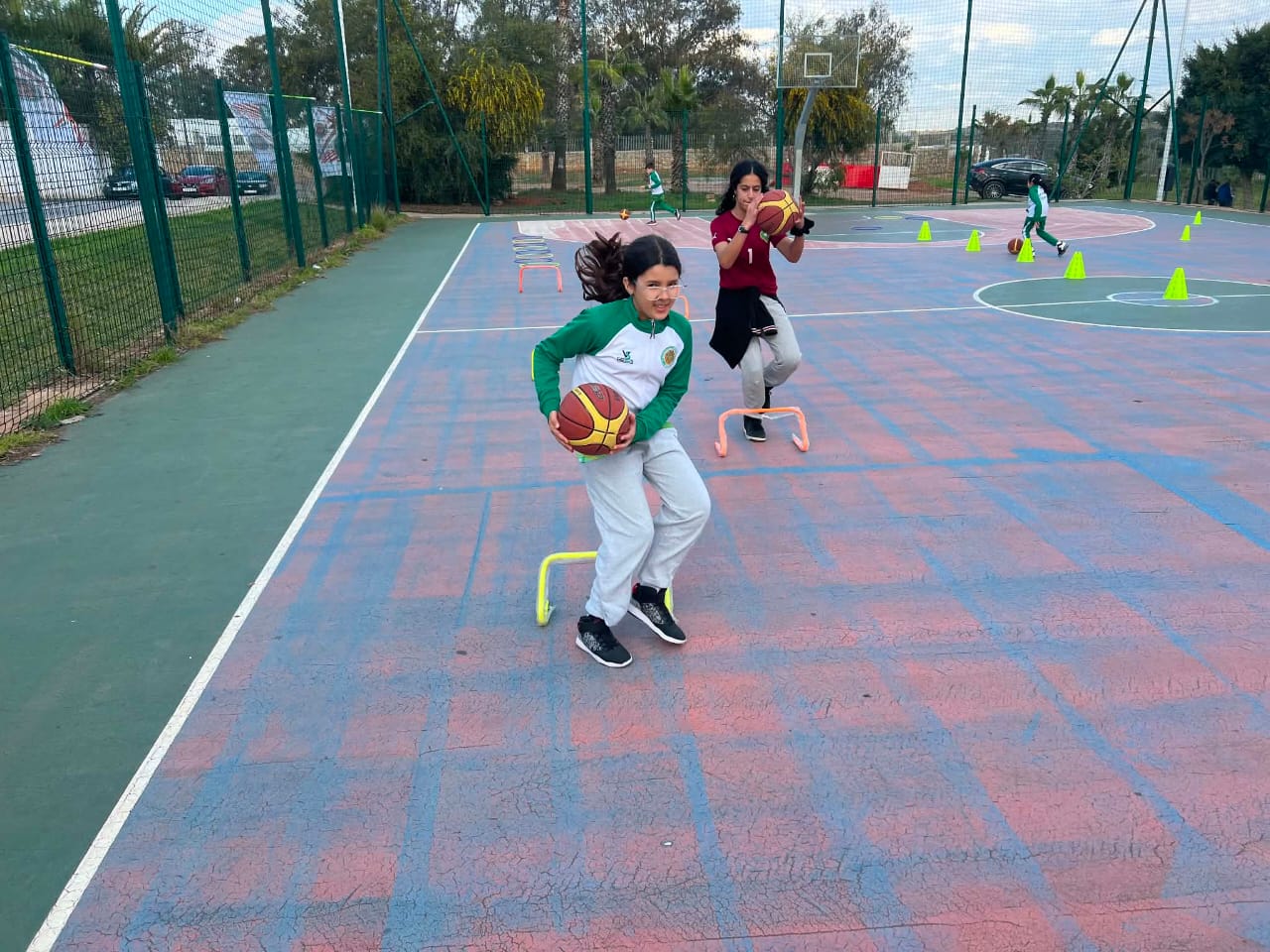 Joueuses d'Essahoua Kids franchissant des haies de coordination balle en main